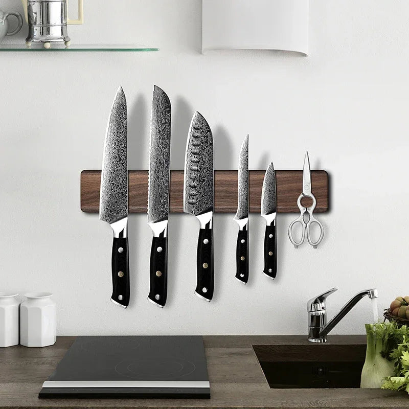 Damascus kitchen knives on wooden magnetic strip, black handles, modern kitchen setup