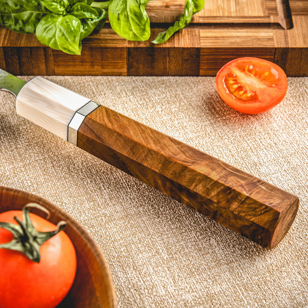 Precision kitchen knife with wooden handle, fresh tomato and basil on cutting board