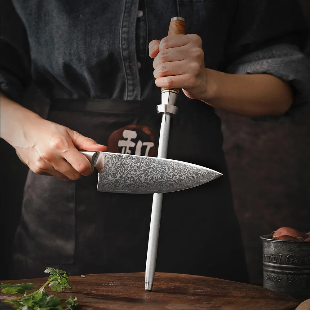 Person sharpening a Damascus chef knife with a honing steel on a wooden cutting board