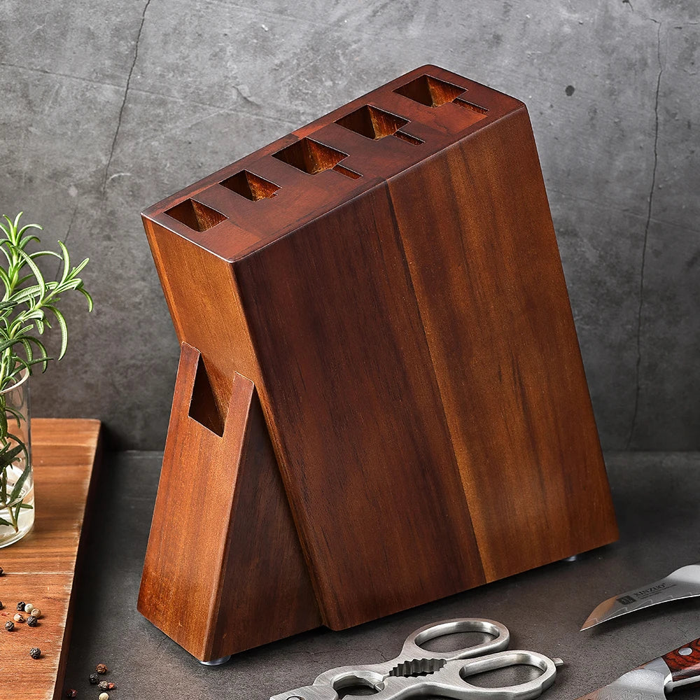 Solid wood knife block with slots for kitchen knives, scissors, and tools, on dark countertop with rosemary.