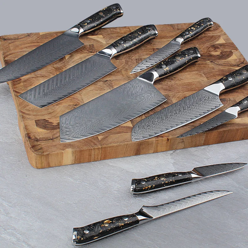 Damascus steel kitchen knives with black speckled handles on wooden cutting board