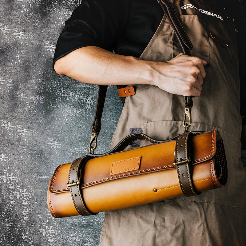 Leather knife roll carrier with shoulder strap, held by chef in apron, ideal for kitchen tool storage